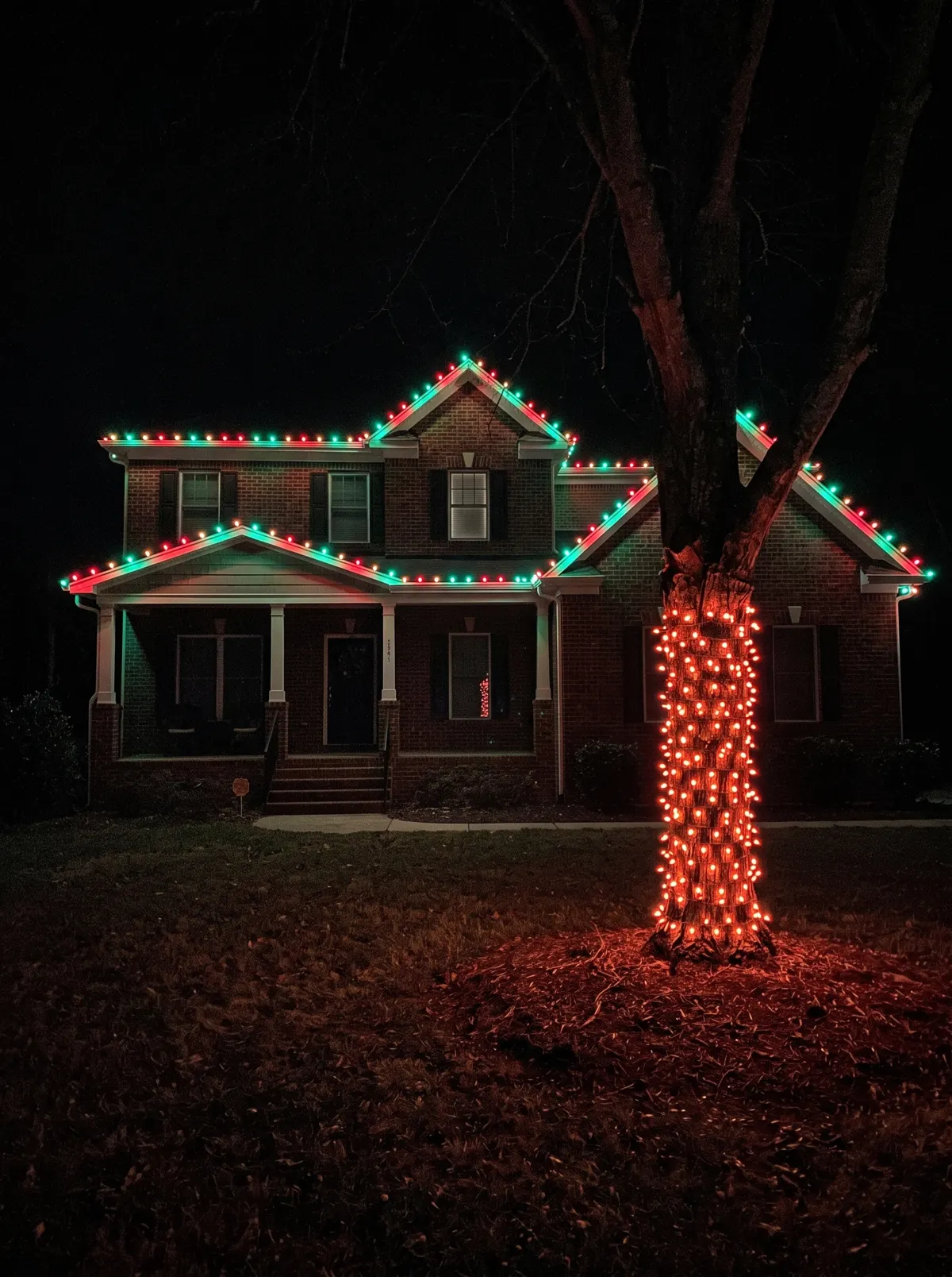 Brick two-story with red and green C9 and a wrapped tree