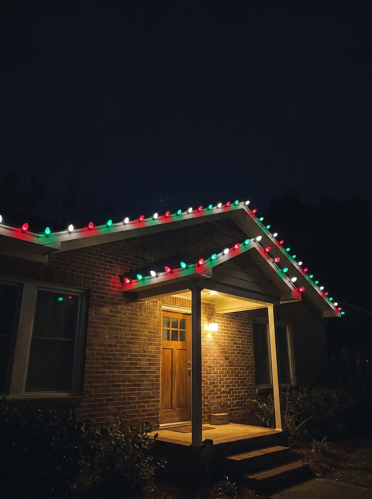 Red, green and white C9 along a brick porch roofline
