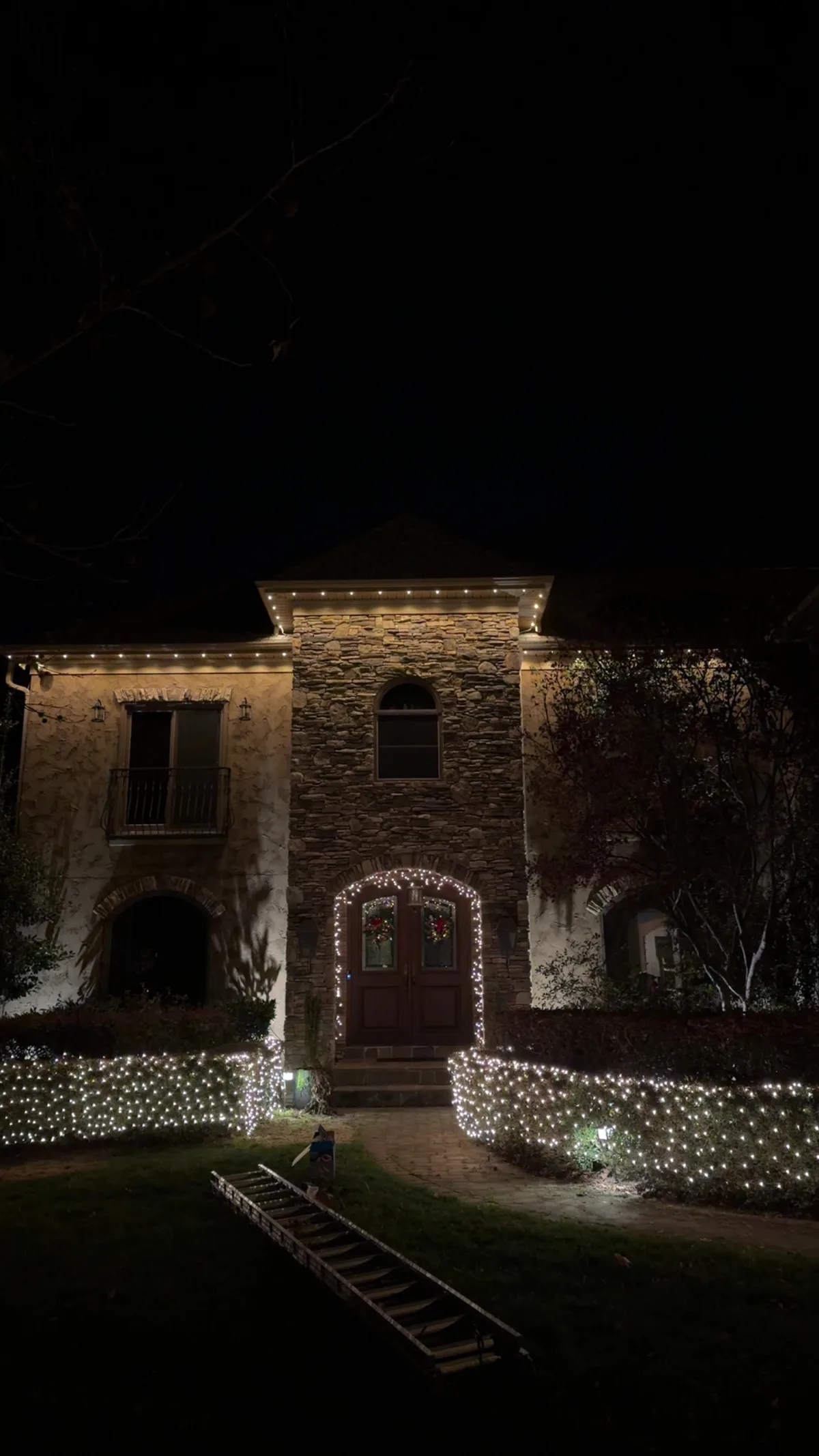 Two-story brick home with warm-white C9 lighting on the rooflines and lit shrubs