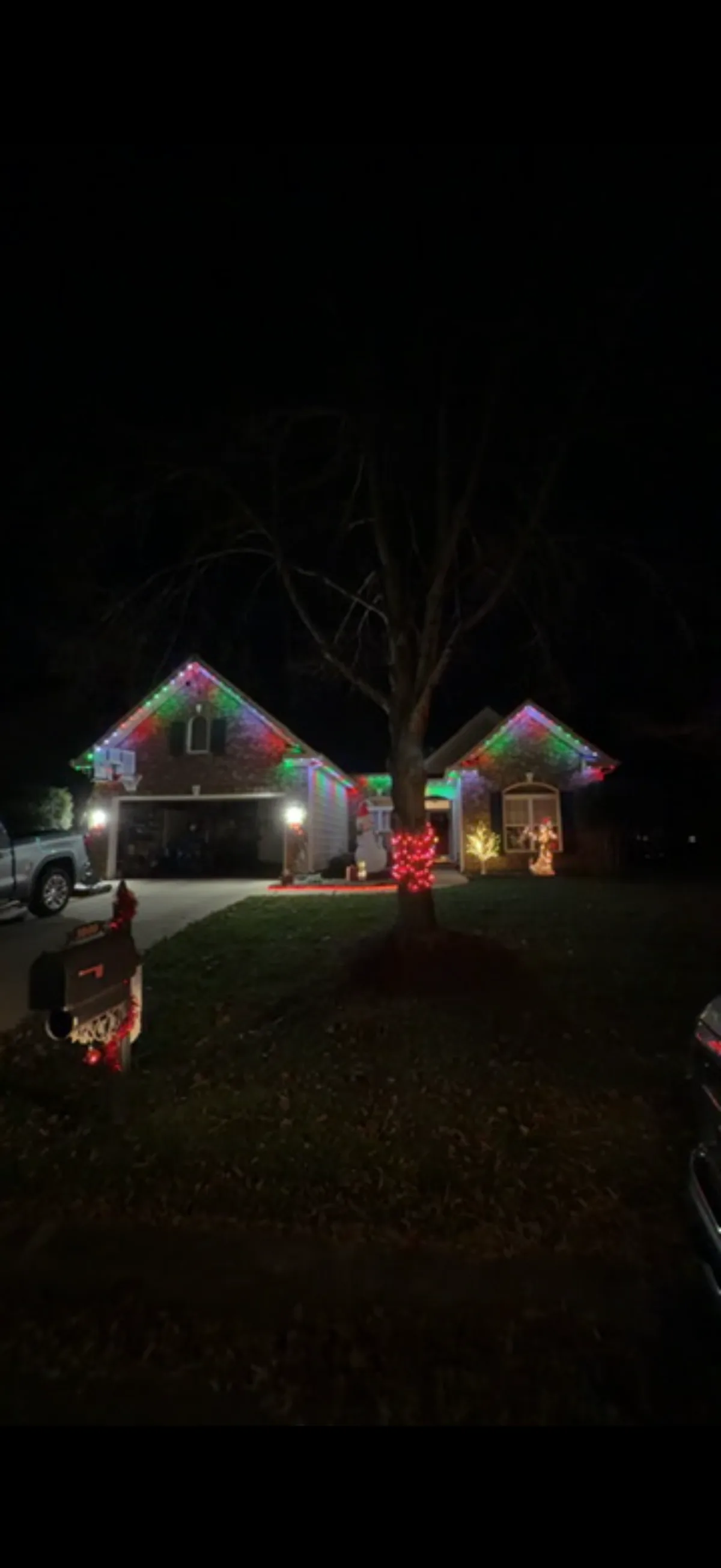 Brick ranch with red and green C9 lighting and a wrapped front-yard tree