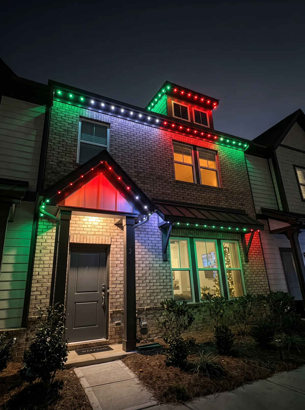 Townhome with red, green and white C9 lighting along the rooflines