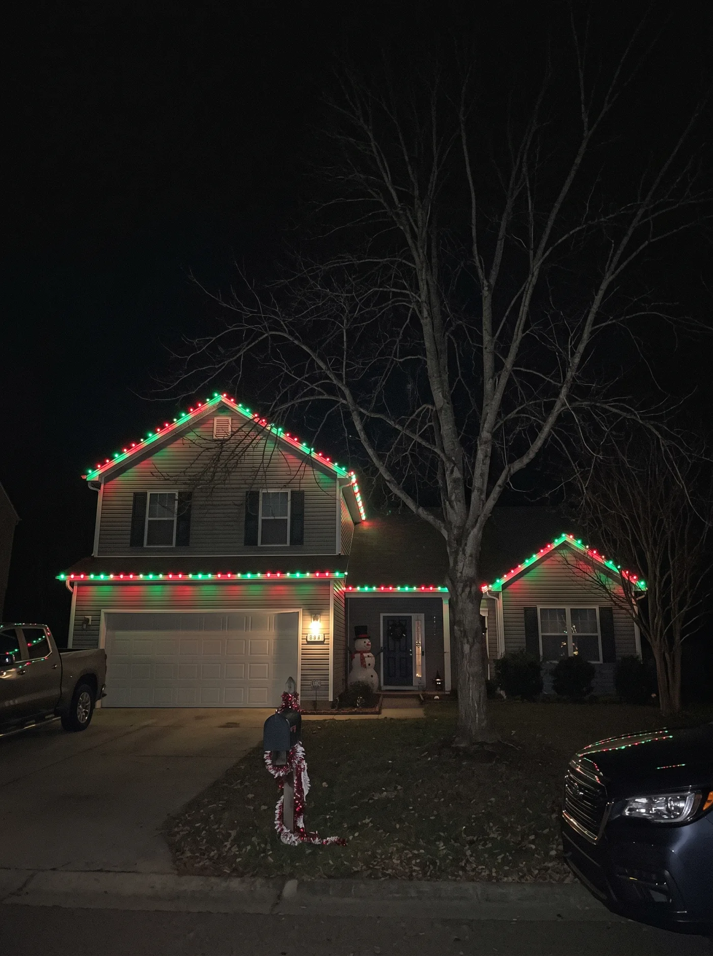 Red and green C9 rooflines with a lit snowman at the front door